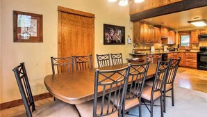 A dining area with a wooden table and chairs, wooden cabinets, and a chandelier. - Storm Meadows Townhouse 24 Town House (Steamboat Springs)