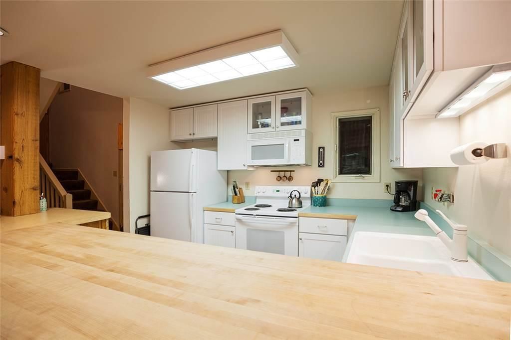 A kitchen with white cabinets, a stove, a microwave, and a sink.