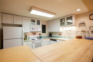 Une cuisine compacte avec des meubles blancs, un plan de travail en bois et un four à micro-ondes.