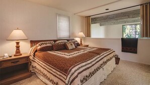 A bedroom with a large bed, two bedside lamps, a window with curtains, and a wall-mounted artwork. - Storm Meadows Townhouse 4 Town House (Steamboat Springs)