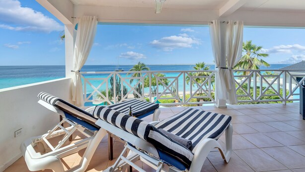Un balcone con due lettini, una ventola a soffitto e vista sull'oceano.