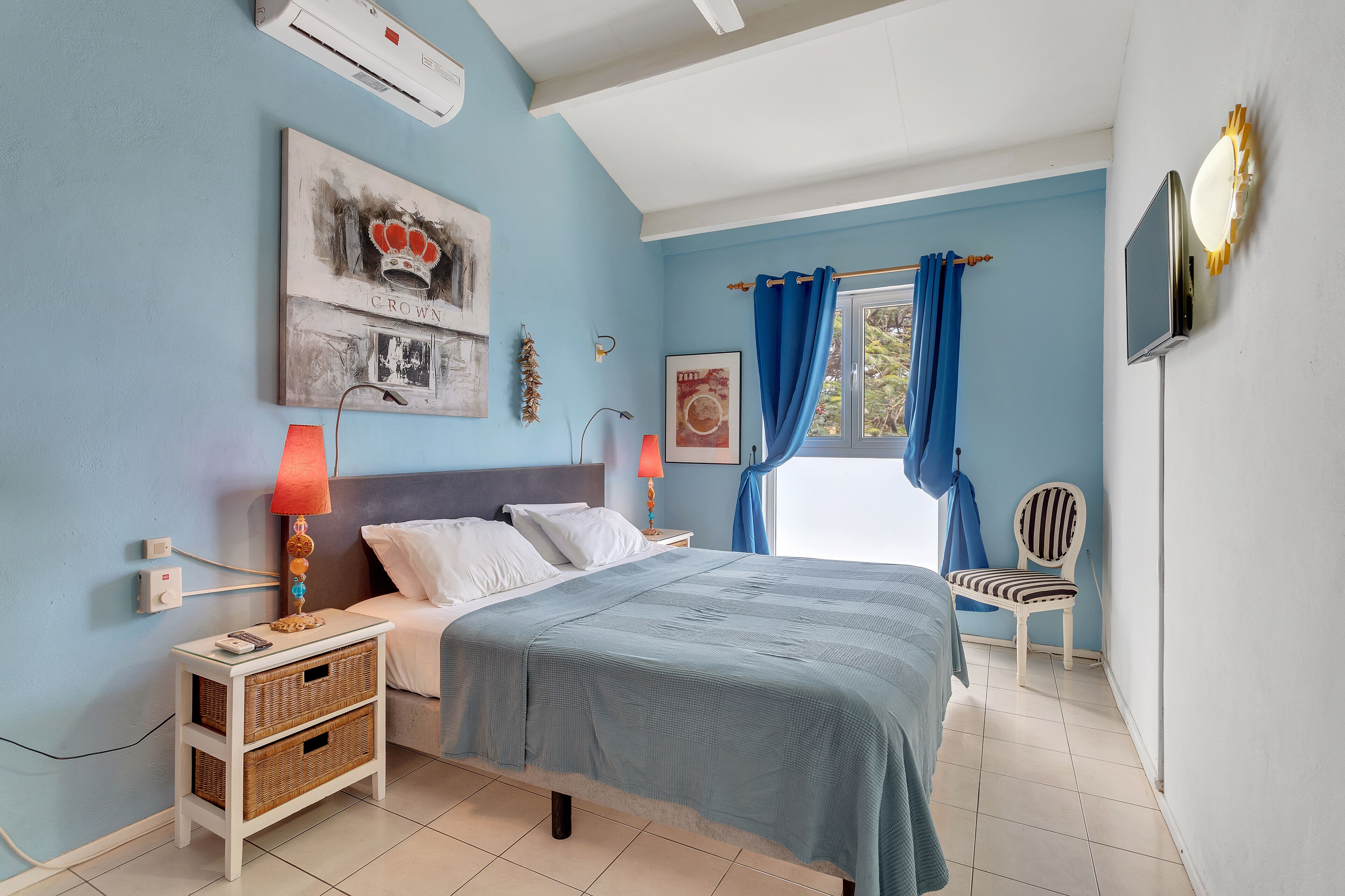 A bedroom with a bed, bedside tables, a chair, and artwork on the walls.