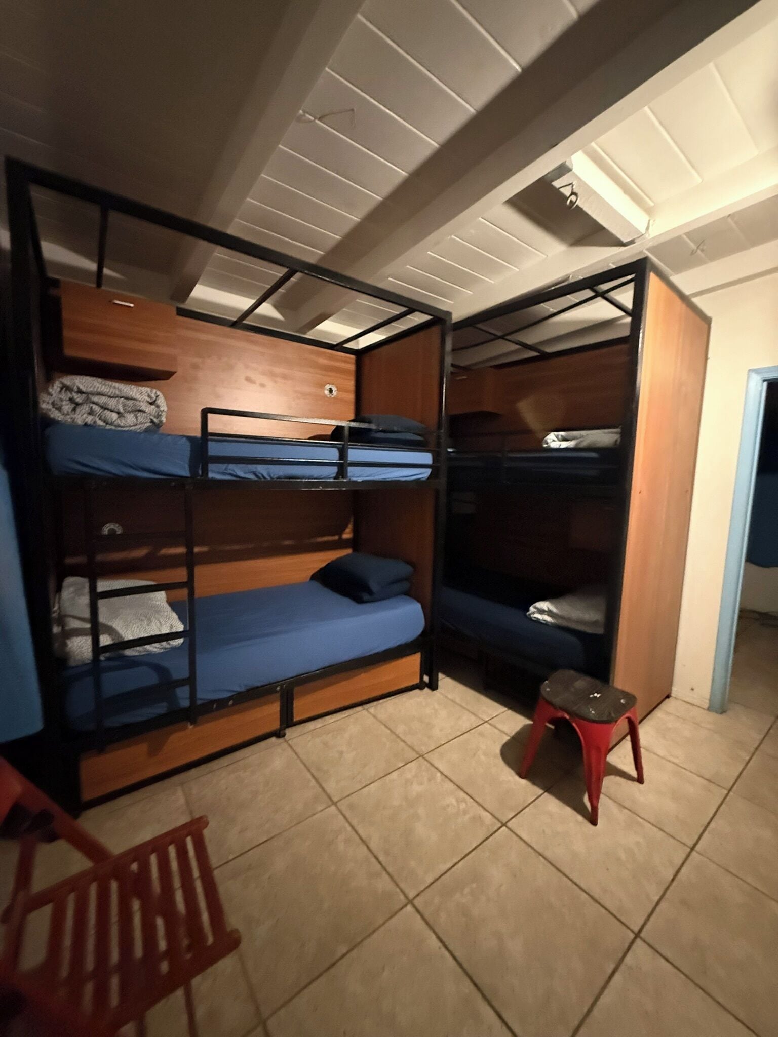 A room with bunk beds, a small stool, and a chair.