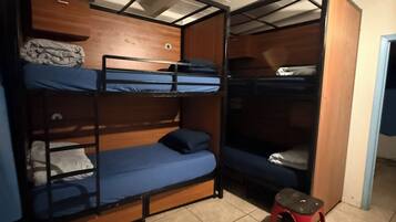 A room with bunk beds, a small stool, and a chair.
