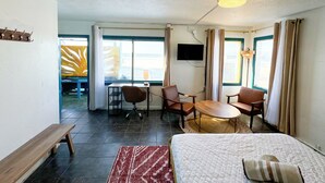 Habitación de hotel con cama, escritorio, dos sillas, televisor y ventana con cortinas.