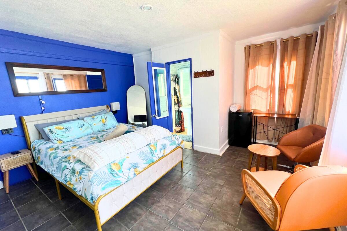 Une chambre à coucher avec un lit, une chaise, un bureau et un miroir.