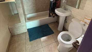 A bathroom with a bathtub, toilet, sink, and shower curtain.