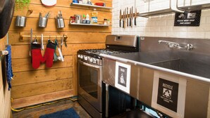Una cocina con paredes de madera, electrodomésticos de acero inoxidable y varios utensilios y recipientes colgados en la pared.