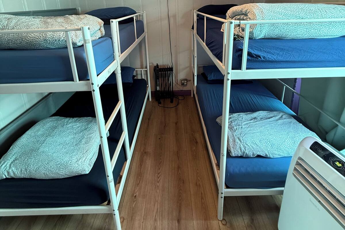 Une chambre avec deux lits superposés, un radiateur et une fenêtre.