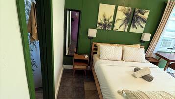 Een slaapkamer met een bed, nachtkastje, spiegel en een deur naar een andere kamer.