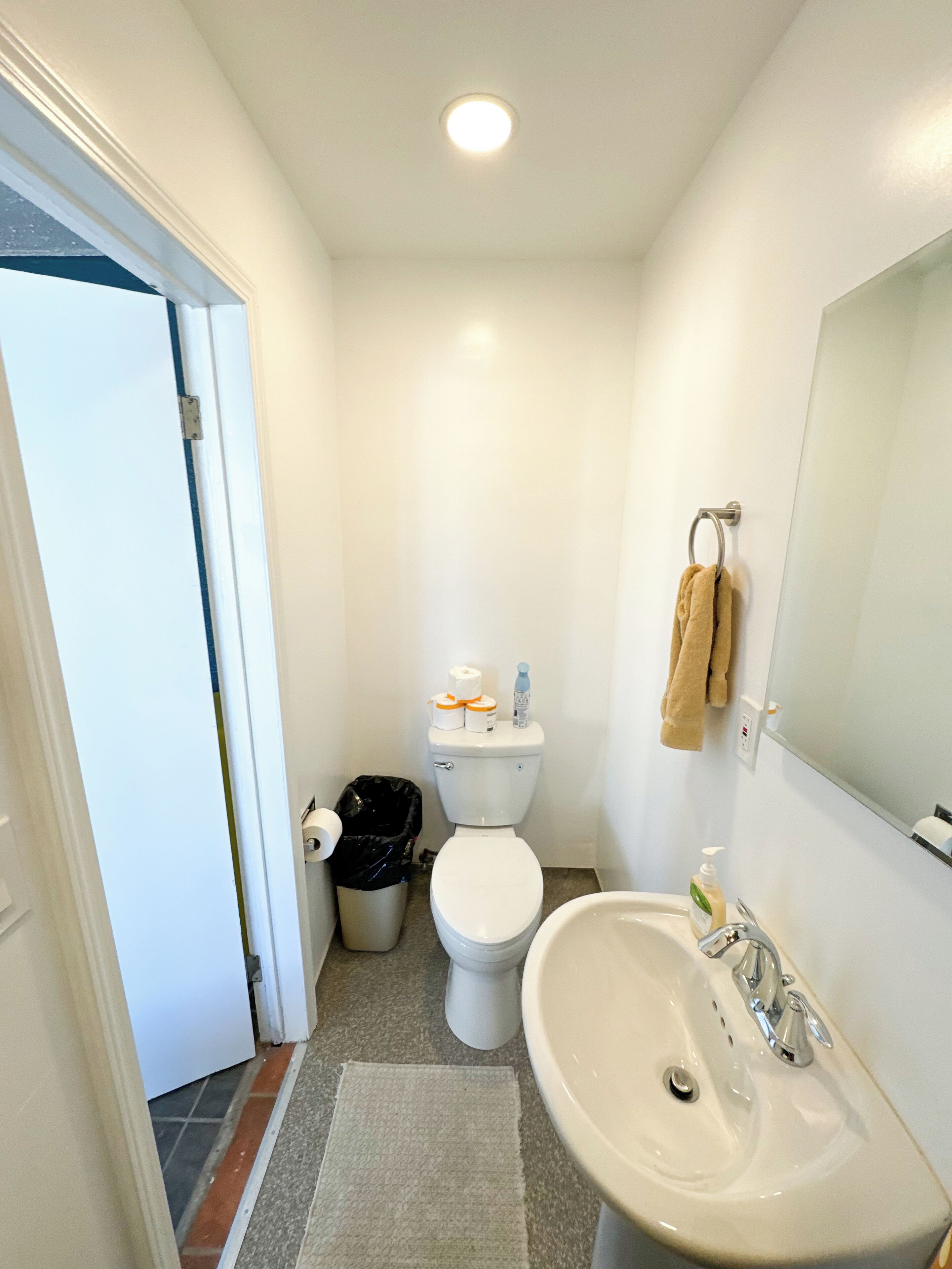 A small, clean bathroom with a toilet, sink, and mirror.
