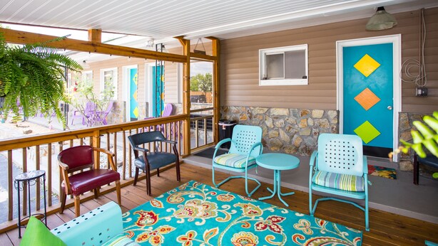 A covered outdoor seating area with wooden furniture and a colorful patterned rug. - Sunset Motel (Murphy)
