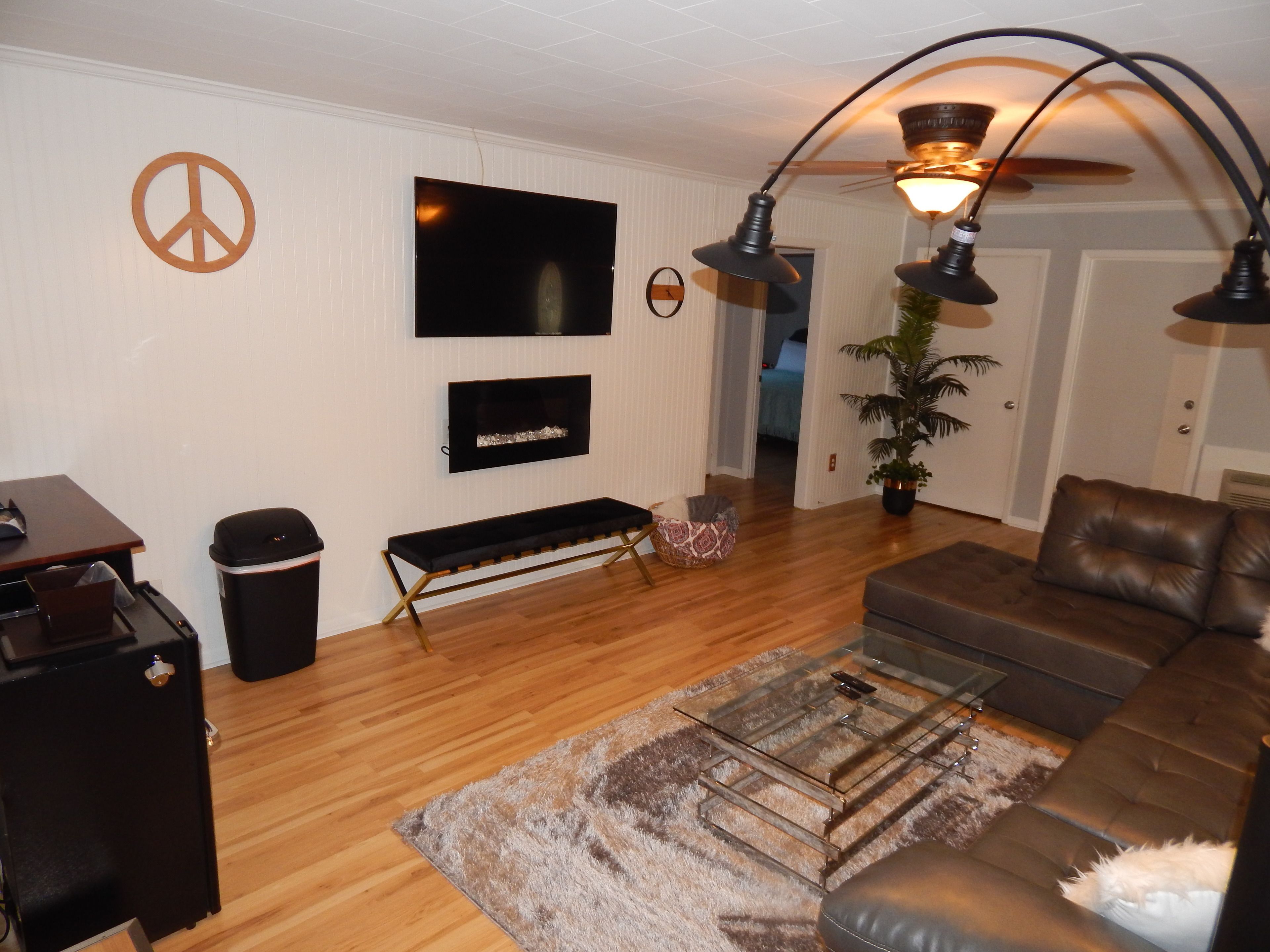 A living room with a TV, sofa, coffee table, and a peace sign on the wall.