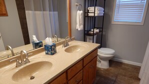 A bathroom with two sinks, a toilet, and a towel rack.