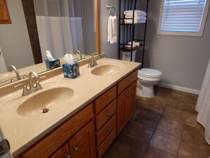 A bathroom with two sinks, a toilet, and a towel rack.