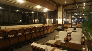 Ein Restaurant mit einer langen Theke, Barhocker und mehreren Tischen mit Stühlen.