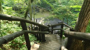 Eine Holztreppe führt zu einem bewaldeten Gebiet mit Blick auf ein Gebäude in der Ferne.