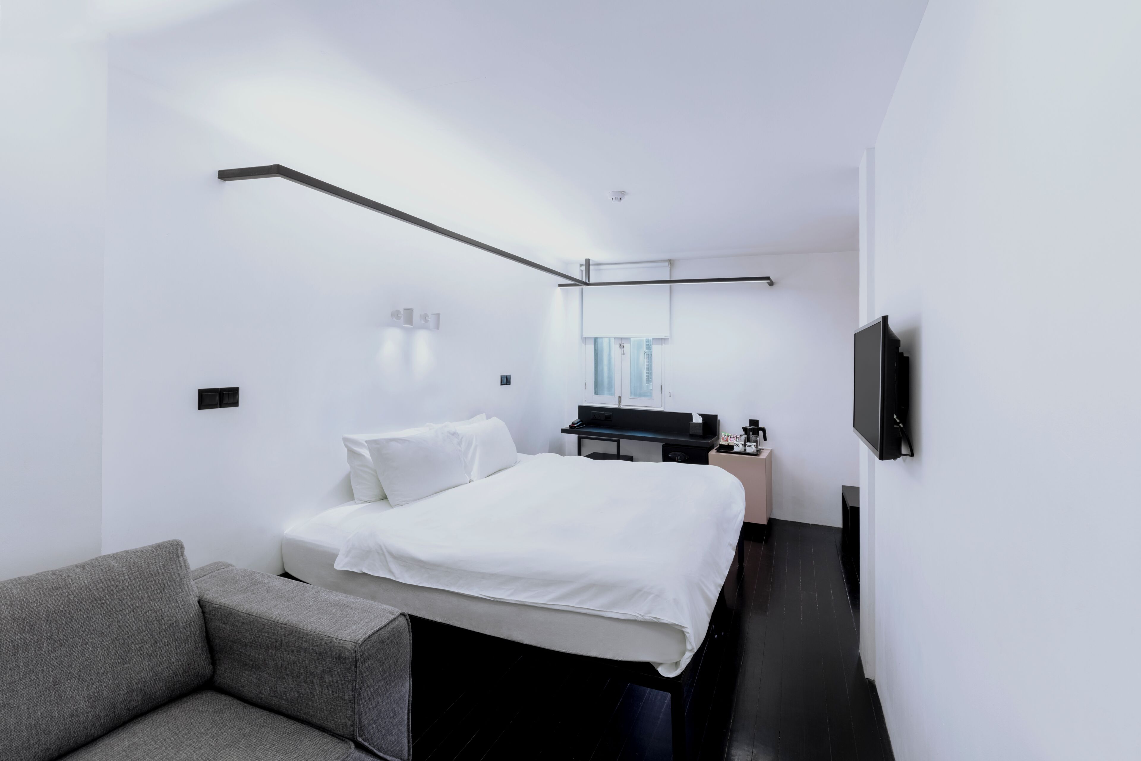 Une chambre d’hôtel moderne équipée d’un lit, d’un bureau, d’une chaise, d’une télévision et d’une fenêtre.