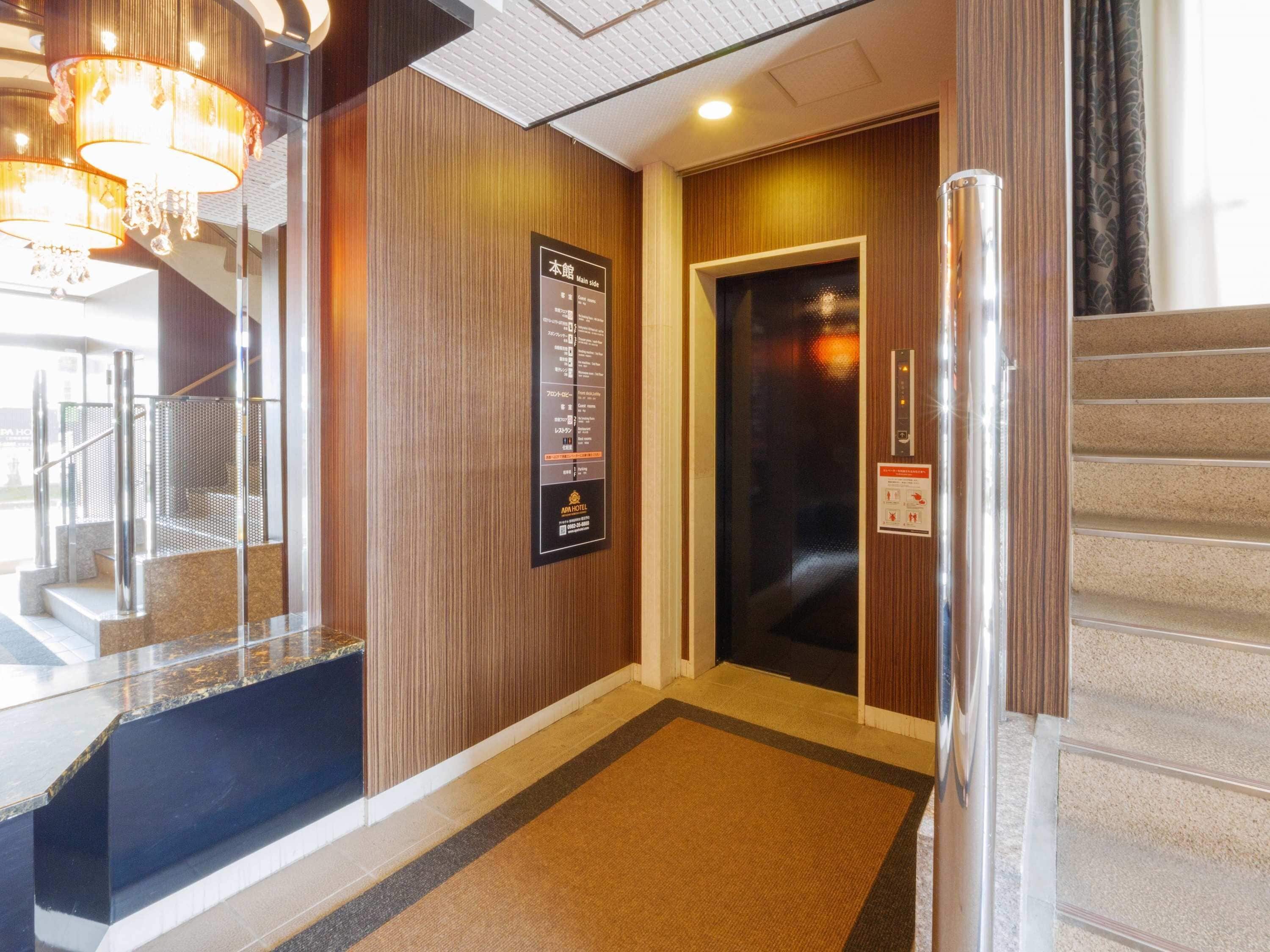 A hotel lobby with a reception desk, a staircase, and an elevator.