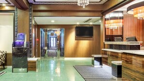 A modern hotel lobby with a reception desk, a digital check-in kiosk, a chandelier, and a television mounted on the wall. - APA Hotel Miyazaki Nobeoka Ekimae (Nobeoka)