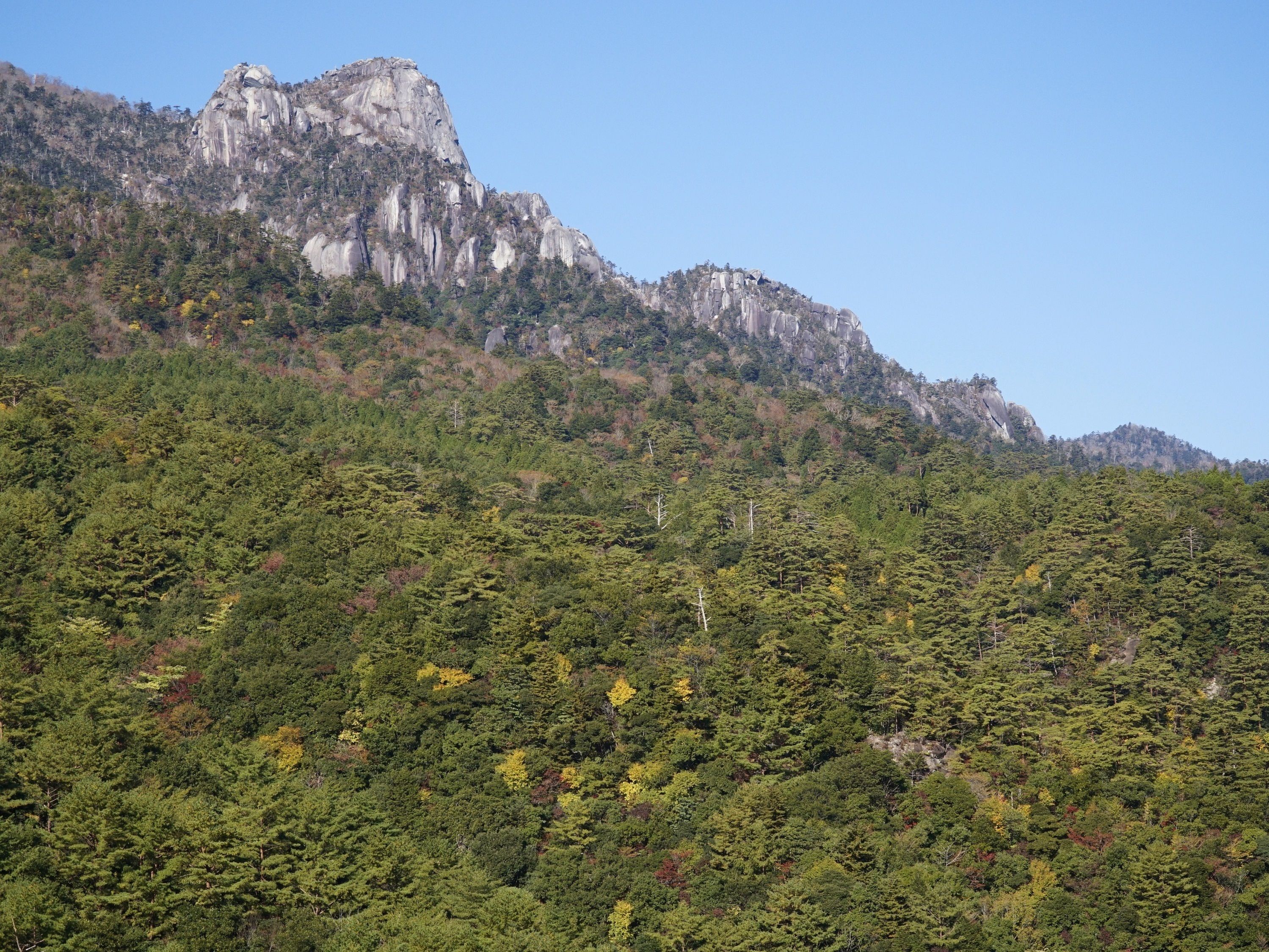 Eine gebirgige Landschaft mit dichtem Wald und steilen Felswänden.