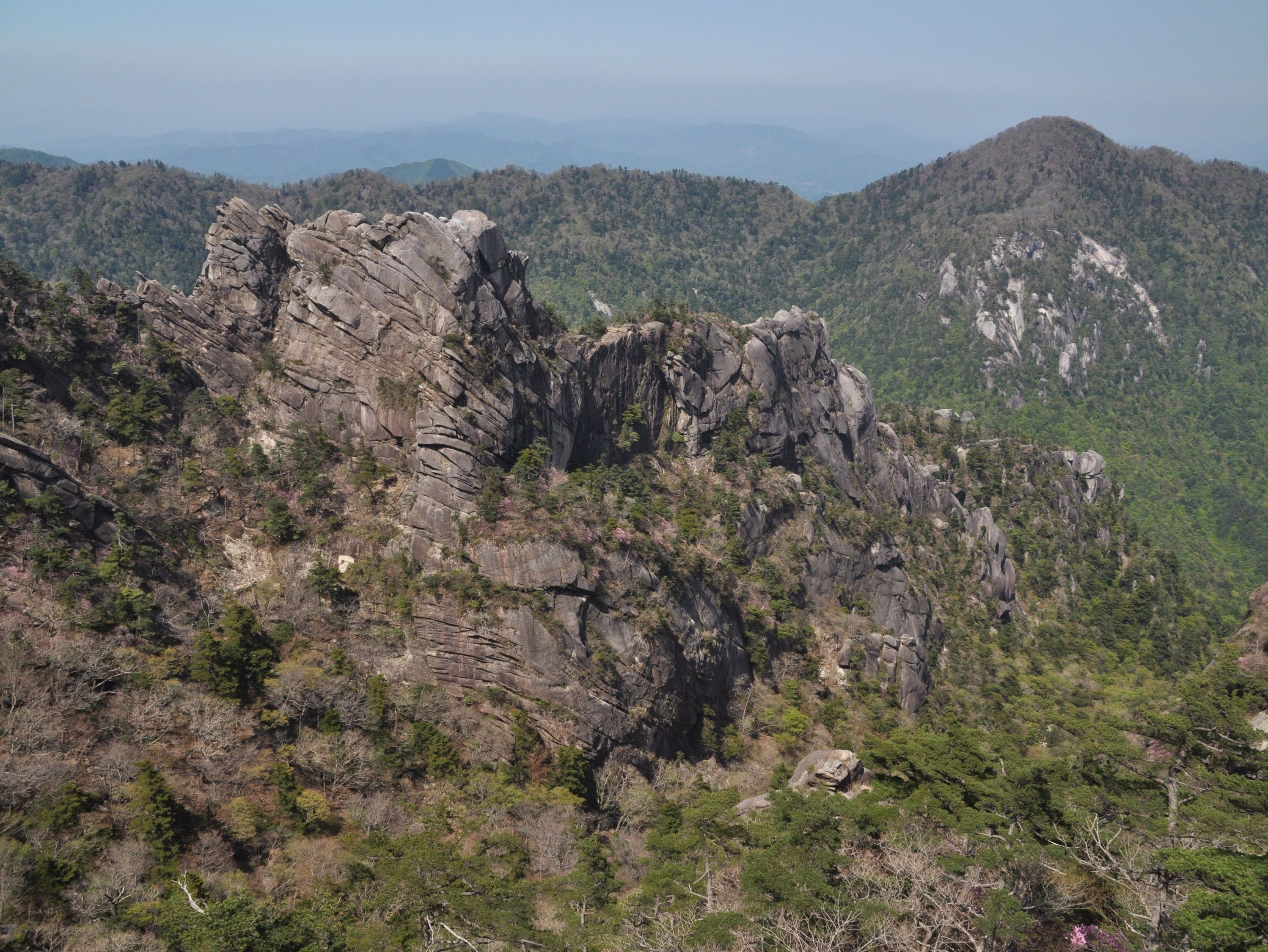 A rugged mountain landscape with rocky outcrops and dense forest.