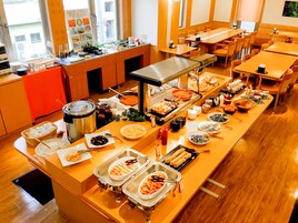 Montaje tipo bufé con diferentes opciones de comida y una zona de estar con mesas y sillas.