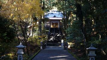 A traditional Japanese temple with a gravel pathway leading to the entrance, surrounded by trees and stone lanterns.