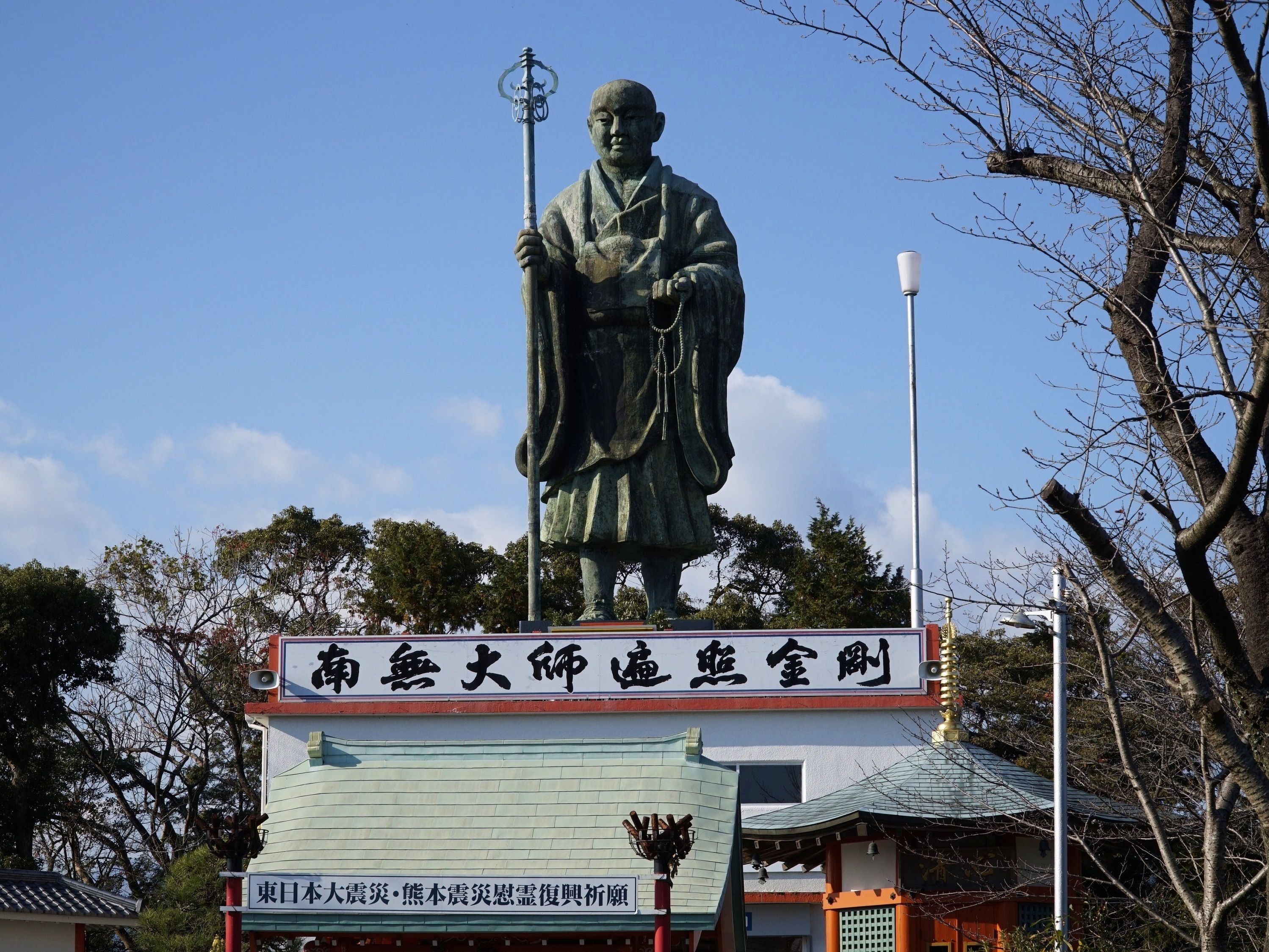 Una estatua de una figura histórica sobre un pedestal con un letrero en un idioma extranjero.
