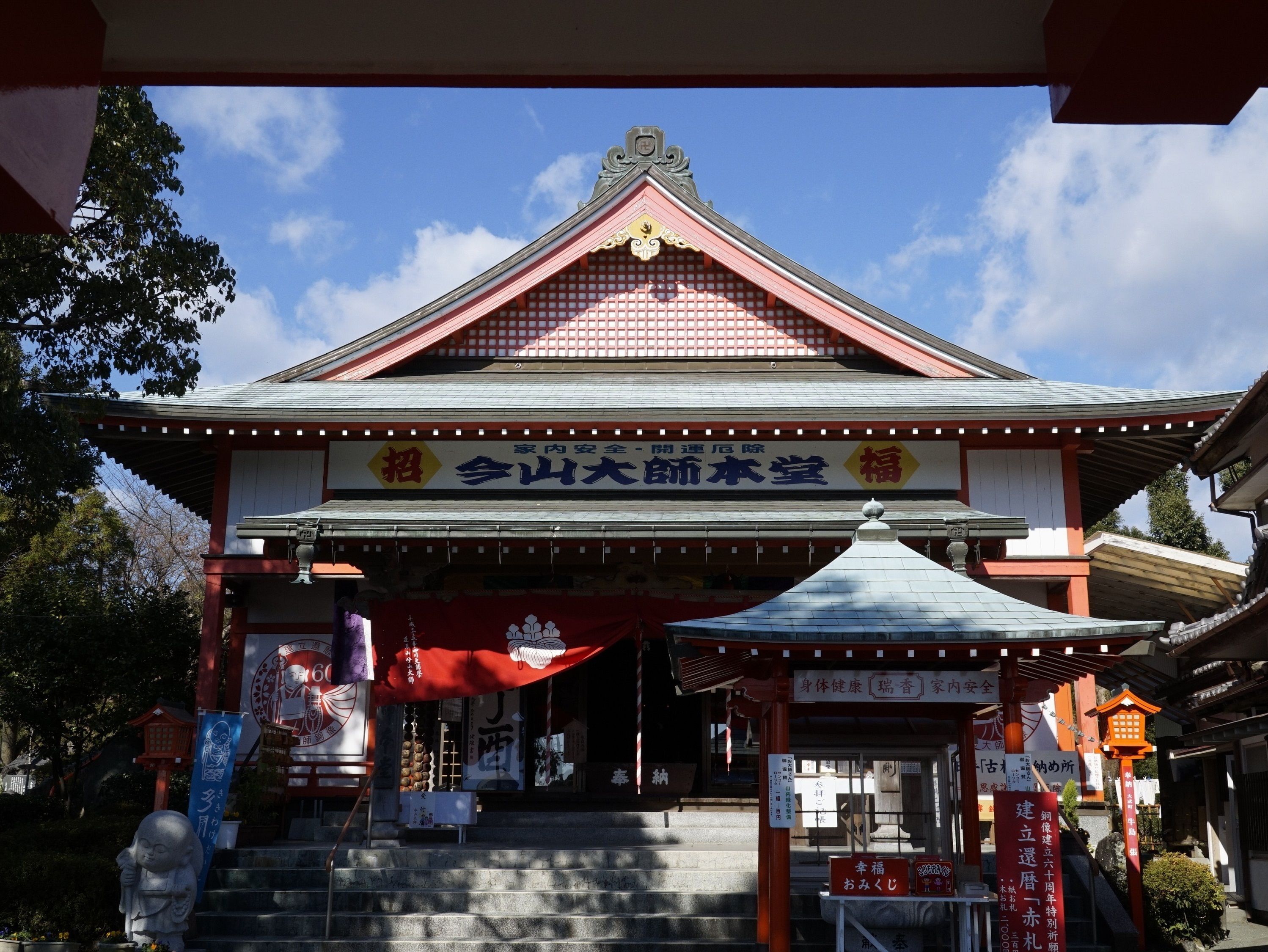 A traditional Japanese building with a red and white color scheme, a tiled roof, and a signboard above the entrance.
