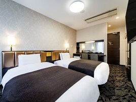 A hotel room with two beds, a desk, a mirror, and a bathroom door.