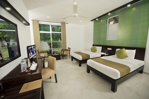 A hotel room with two beds, a desk with a chair, a TV, and a window with curtains.