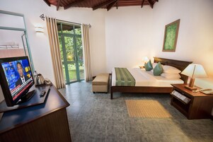 Un dormitorio con cama, mesitas de noche, televisor y vistas al exterior.