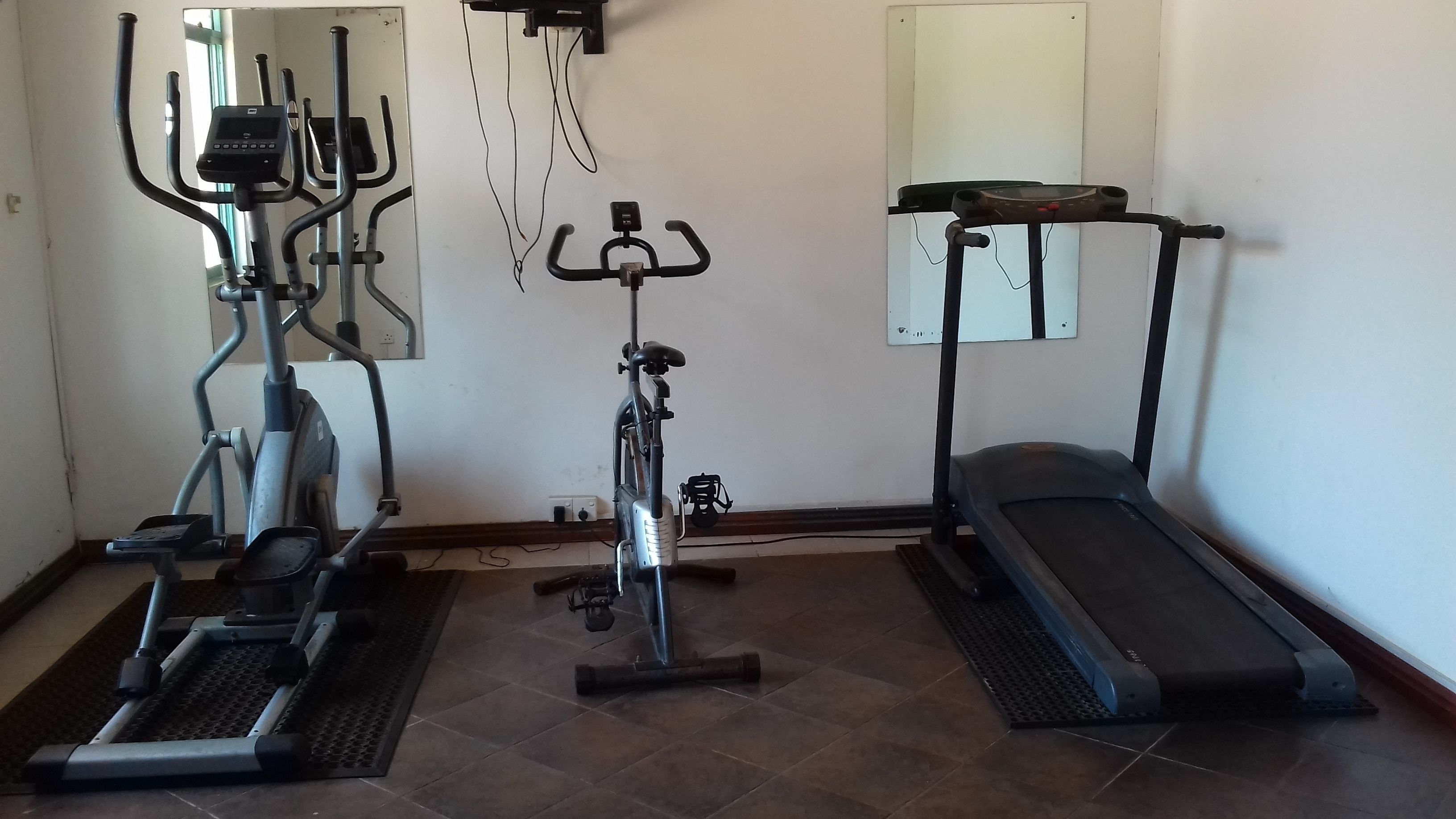 A home gym with a stationary bike, elliptical, treadmill, and weights.