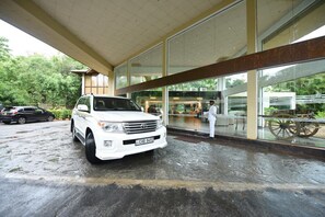A white SUV parked in front of a building with large windows and a covered entrance.