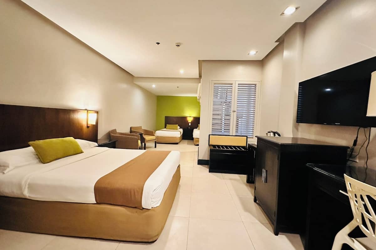 A hotel room with a bed, a desk, a chair, a television, and a window with blinds.