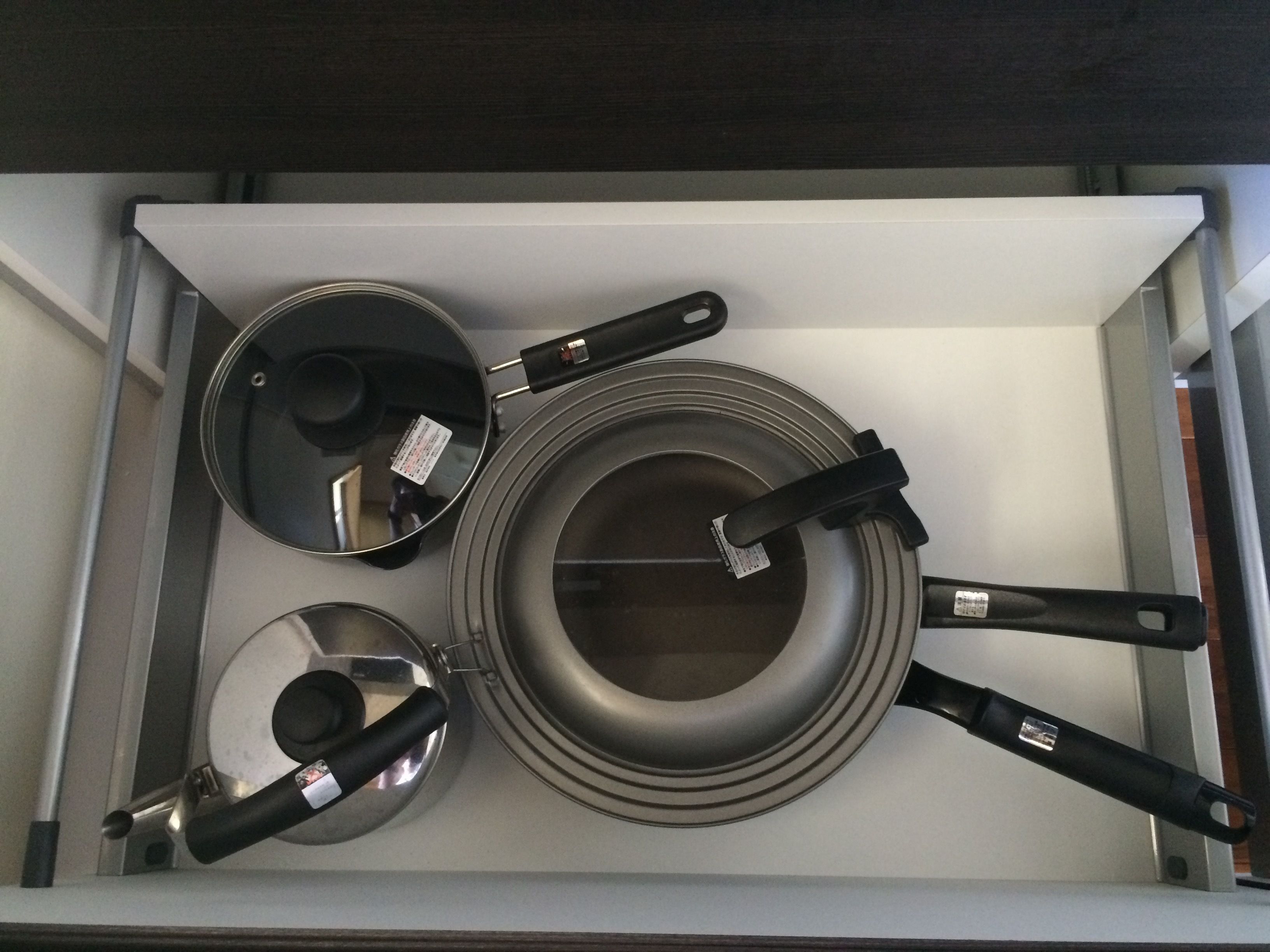 A kitchen drawer with various pots and pans.