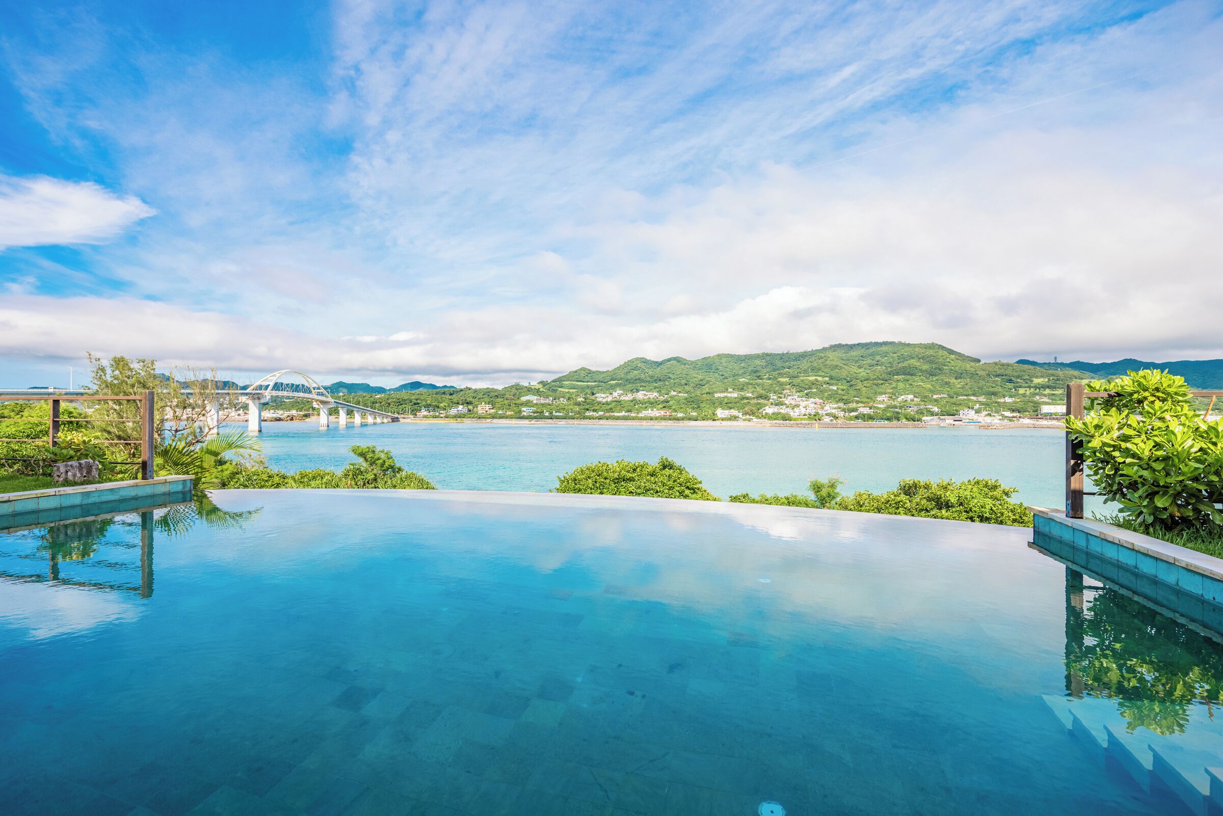 An infinity pool with a clear view of a bridge and a mountainous landscape.