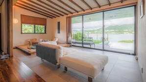 A modern bedroom with a large sliding glass door leading to an outdoor area, a bed, a desk, and a chair. - Sesoko Sansui (Motobu)
