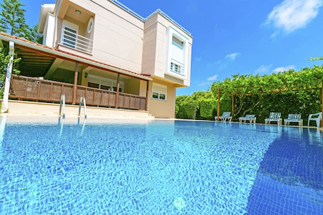 Una piscina al aire libre, sombrillas, sillones reclinables de piscina