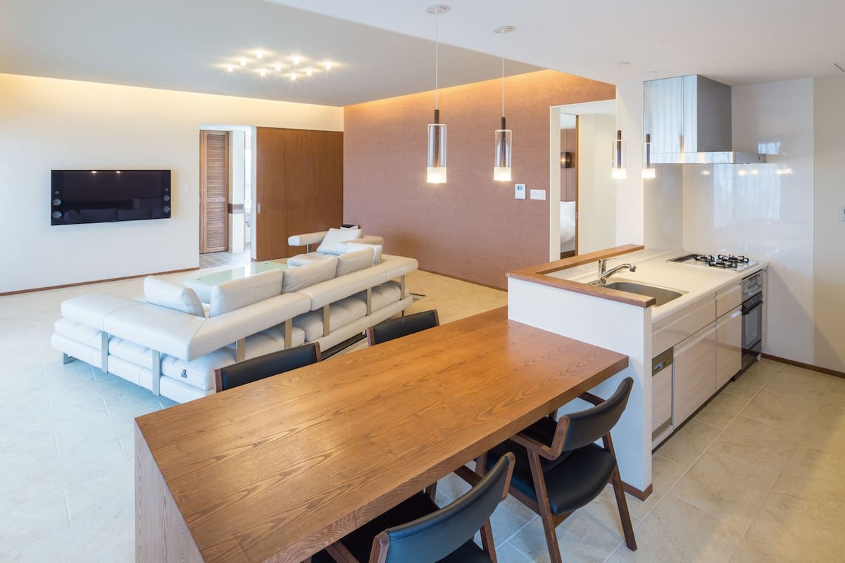 A modern kitchen with a wooden dining table and chairs, a built-in oven, and a large island with a sink.