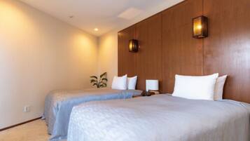 A hotel room with two beds, a wooden headboard, a wall-mounted lamp, and a small plant.