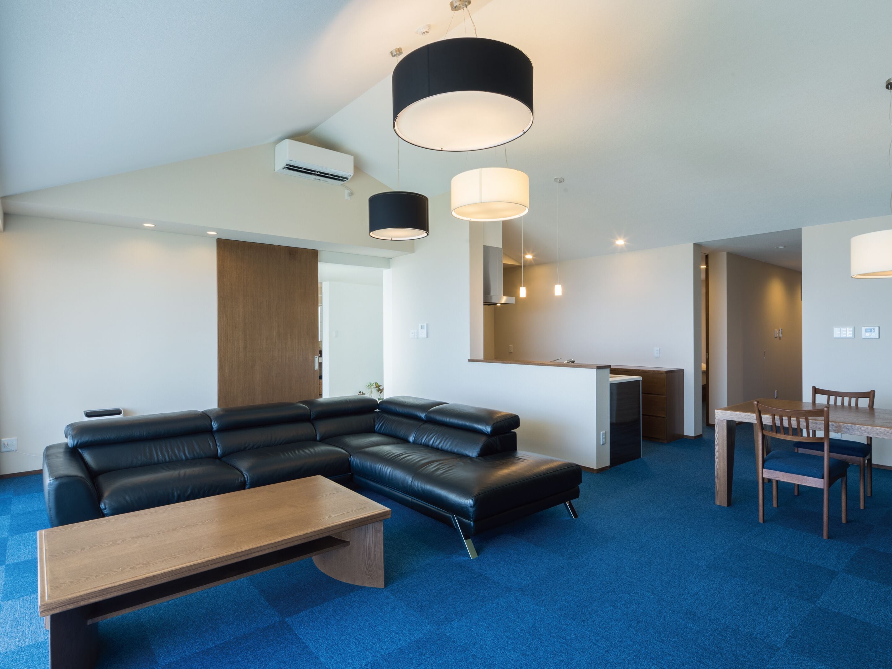 Ein modernes Wohnzimmer mit einer Eckcouch, einem Holztisch und einem Essbereich mit Tisch und Stühlen.