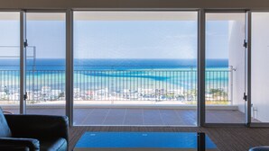 A room with a view of the ocean through large sliding glass doors. - Condominium T-Room (Yomitan)