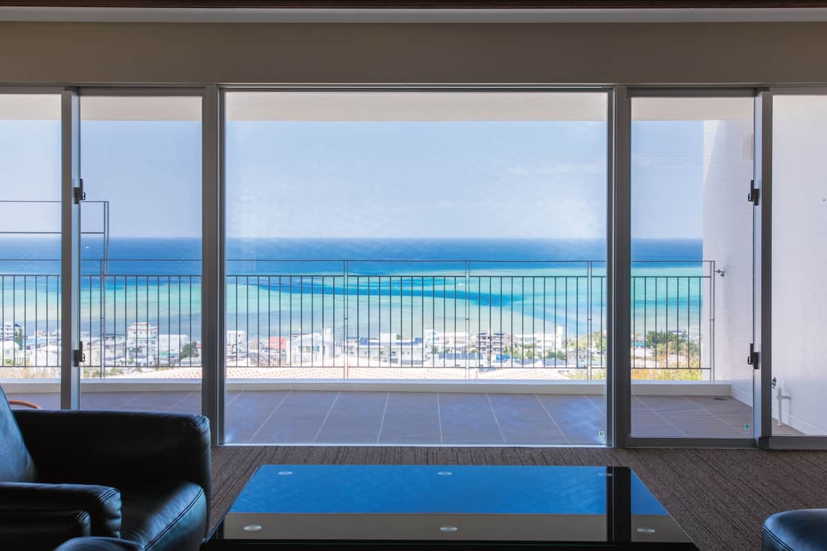 A room with a view of the ocean through large sliding glass doors.