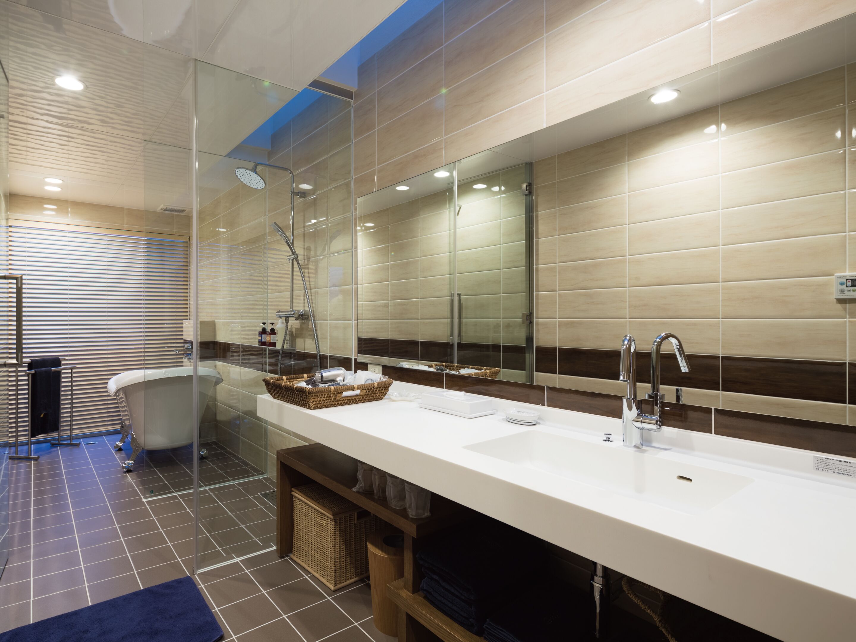 A modern bathroom with a large mirror, a bathtub, a shower, and a vanity with a sink and towel rack.