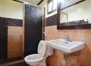 Une salle de bain comprenant des toilettes, un lavabo et une porte ornée d’un motif en bambou.