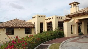 Um edifício com telhado em telhas, janelas grandes e um caminho curvo que leva à entrada.