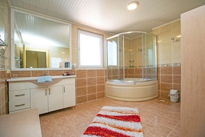 Ein Badezimmer mit einer Badewanne, einer Duschkabine, einem Waschbecken und einem Fenster.