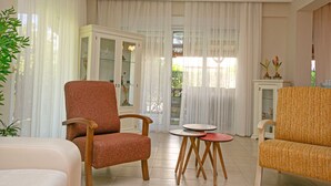 A living room with two armchairs, a small table, and a cabinet with glass doors. - Paradise Town Villa Hazel (Serik)